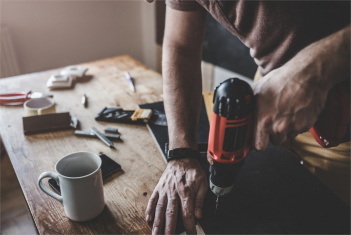 Man drilling laminate with power drill on the table