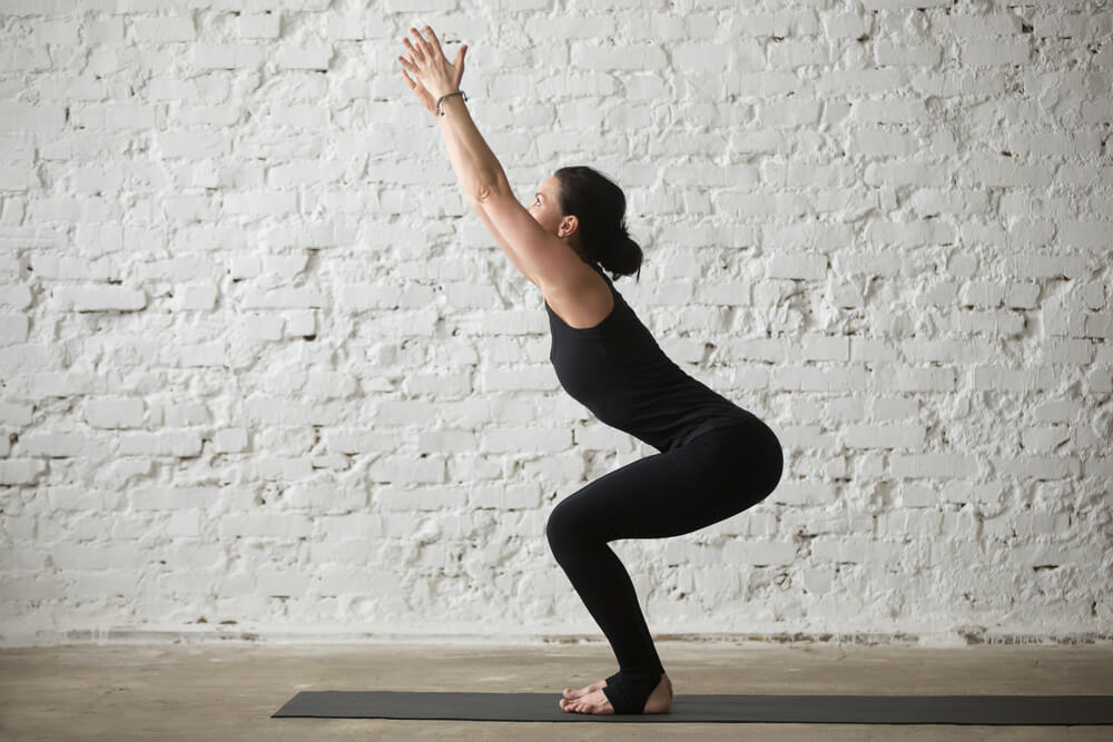 Woman is standing in Utkatasana - chair pose