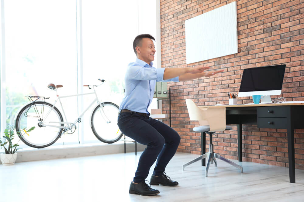 Asian businessman doing exercises at his standing desk