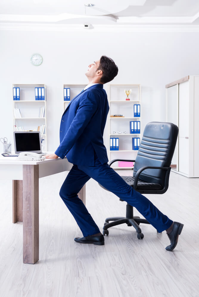 businessman doing lateral leg raise at workplace