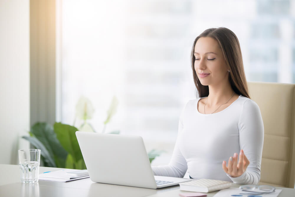 Woman is practicing meditation at the office desk