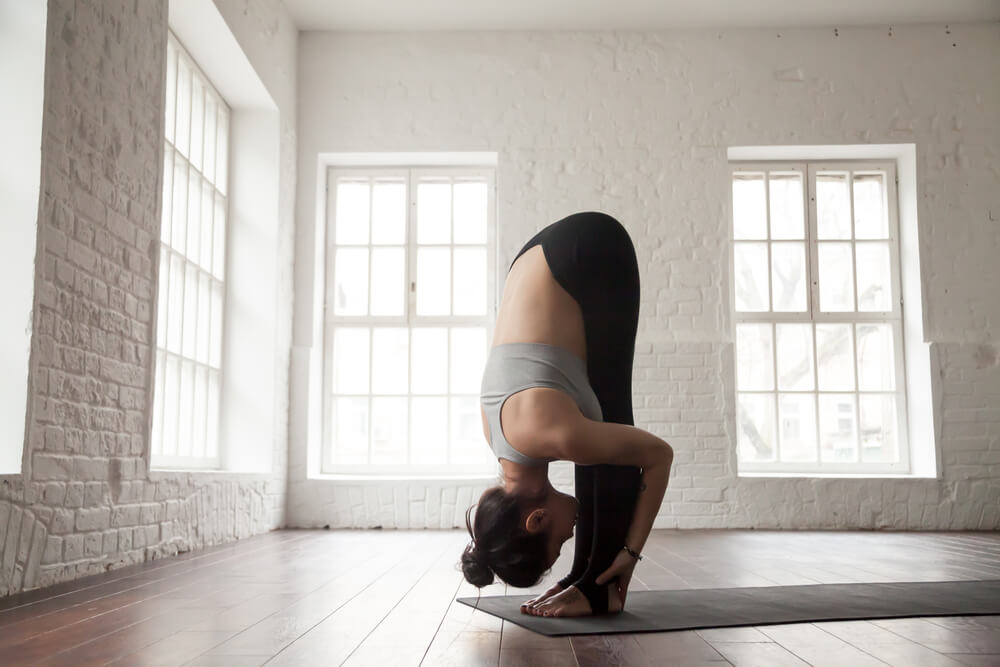 Woman standing in uttanasana - standing forward fold pose 