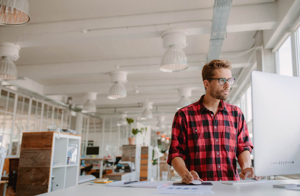 young businessman is working at his height-adjustable standing desk