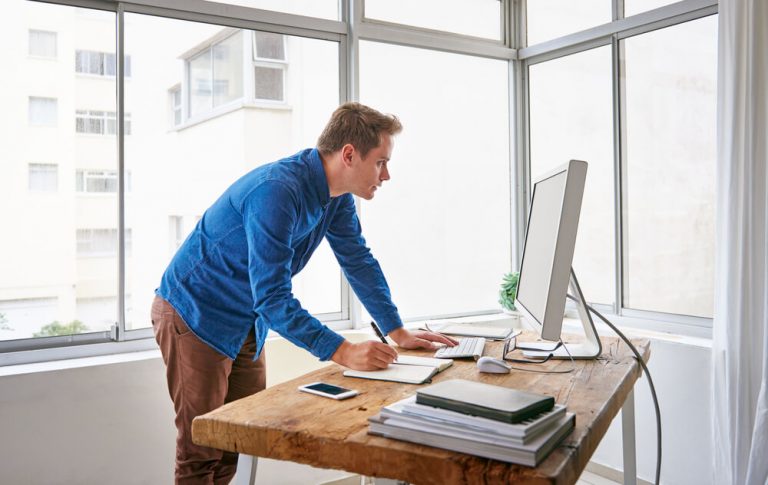 young male entrepreneur standing at his sit-stand desk