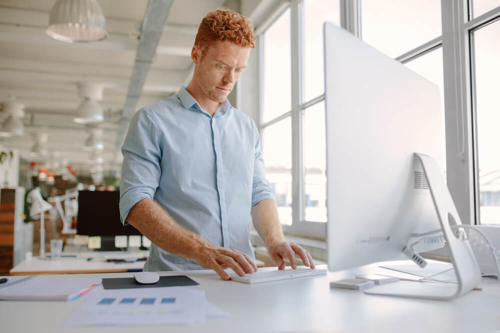 Young man standing at his adjustable office desk