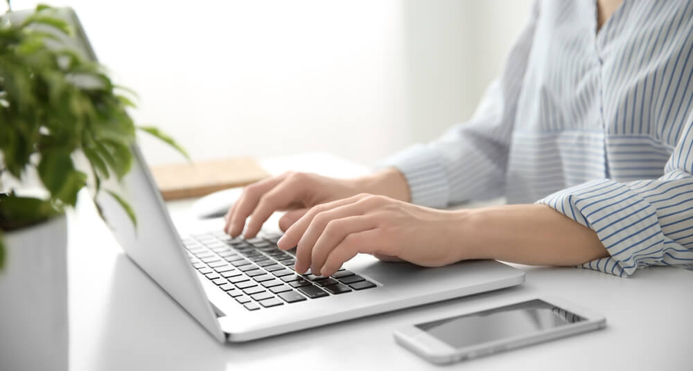 Woman working on computer at her standing desk at home