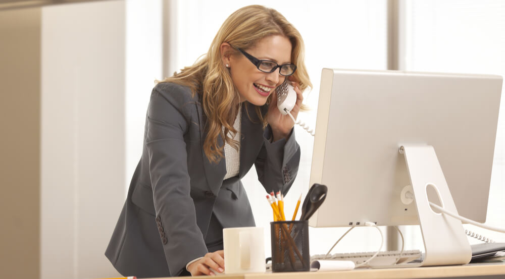 businesswoman is talking over the phone while looking at her computer