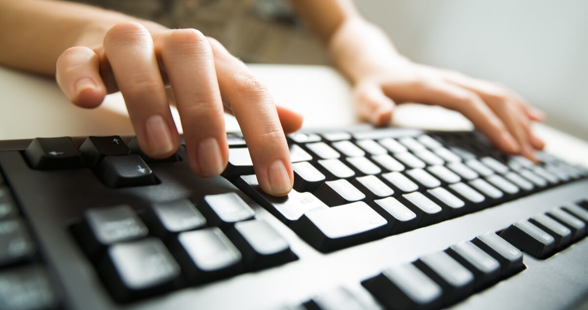 female hands pressing keys of black ergonomic keyboard