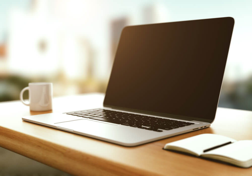 workspace with modern laptop and a coffee cup at sunrise